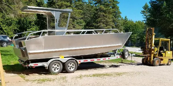 Aluminum boat on a trailer with forklift standing by.